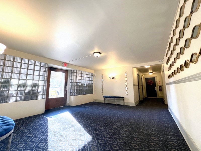 a long hallway with a blue carpet and white walls and a door