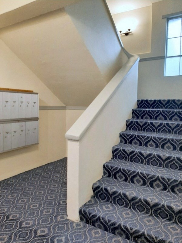 a staircase with blue carpeting and a white railing and a blue carpeted staircase