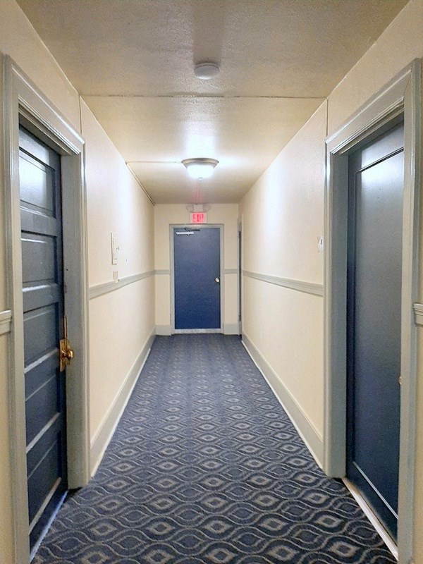 a hallway with two doors and a blue door with a red exit sign