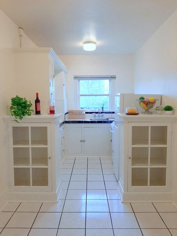 a white kitchen with white cabinets and a window