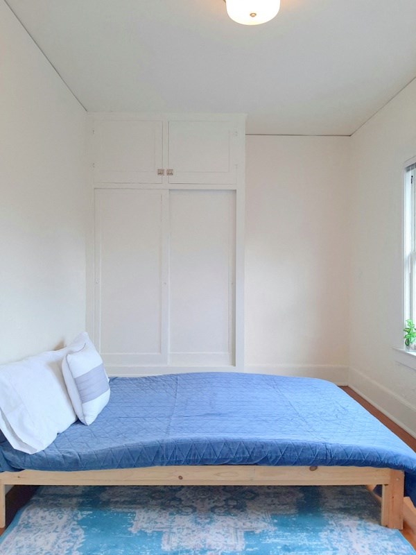 a small bedroom with a bed and a blue rug