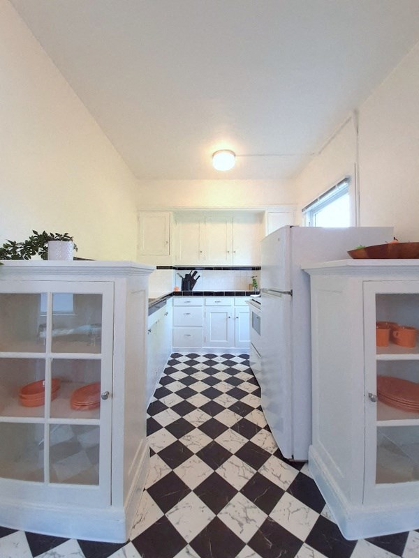 a kitchen with a checkered floor and white cabinets