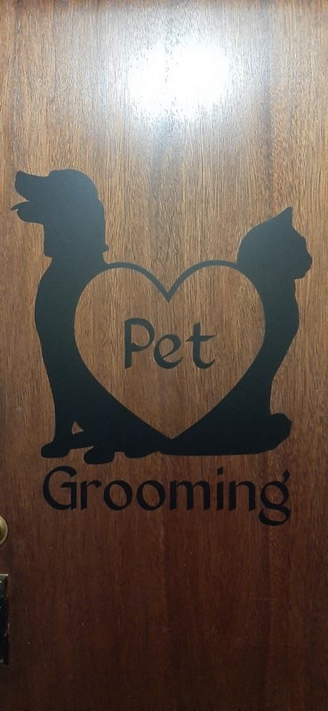a wooden door with a heart with a dog and cat and the word pet grooming