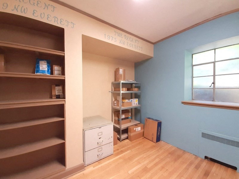 a room with blue walls and a wooden floor and shelves and a window
