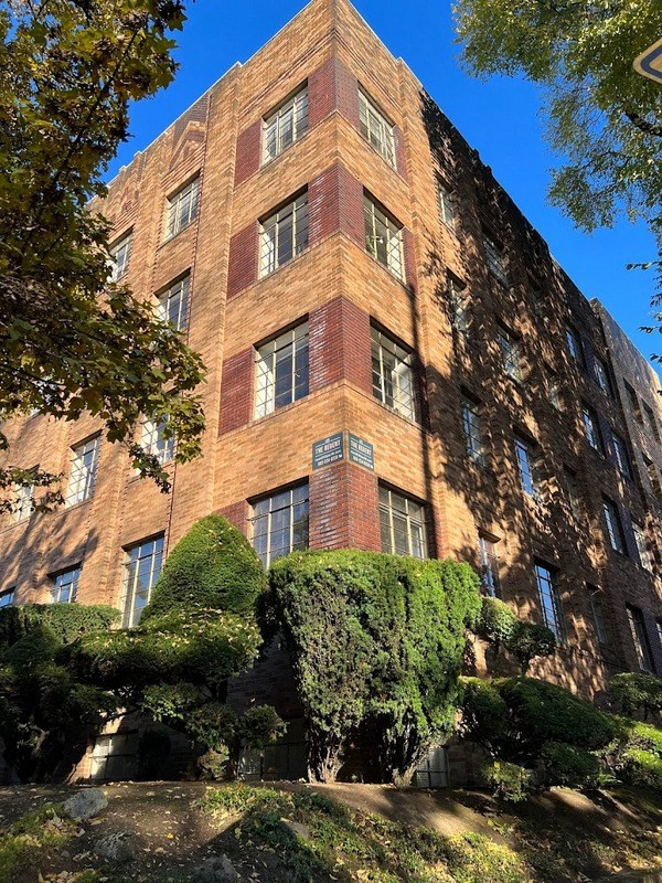 a tall brick building with bushes in front of it