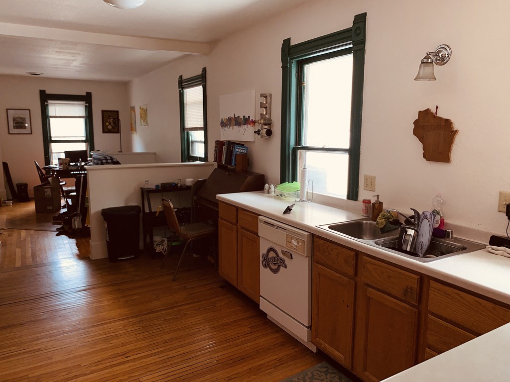 a kitchen and dining room with a wood floor and a sink
