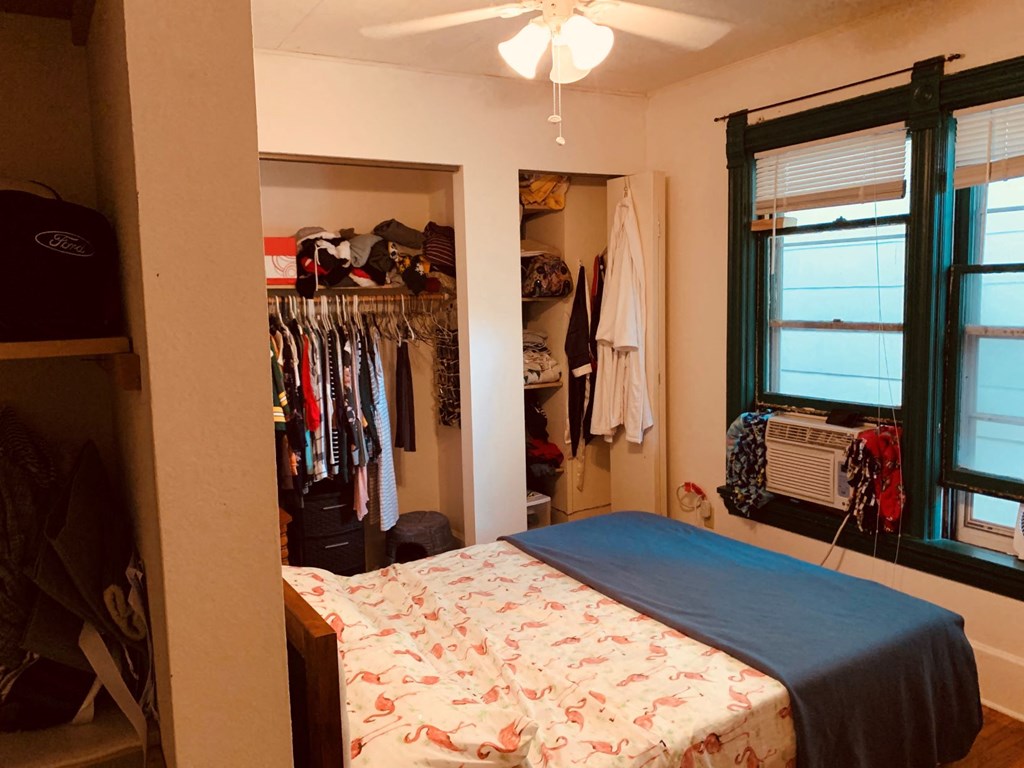 a bedroom with a bed and a closet with clothes in it