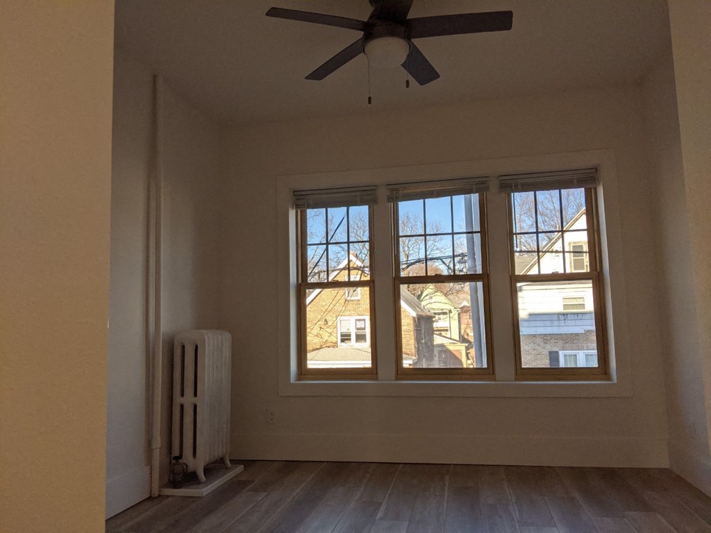 a living room with three windows and a ceiling fan