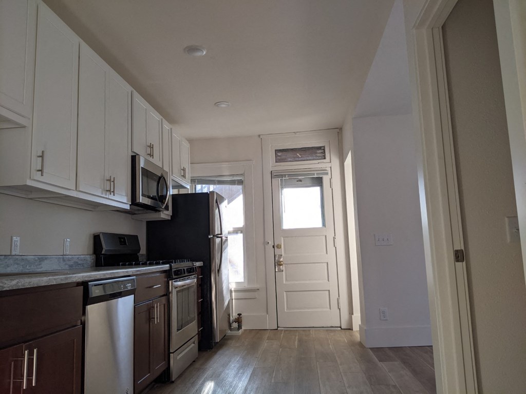 an empty kitchen with white cabinets and a black refrigerator