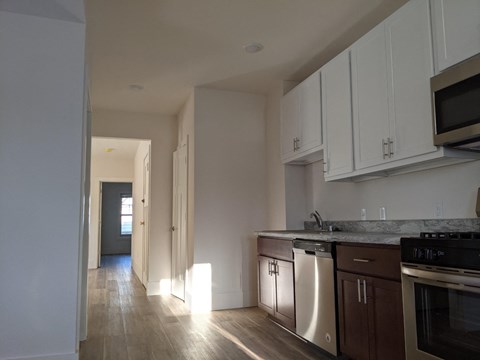 a kitchen with white cabinets and stainless steel appliances and wood floors