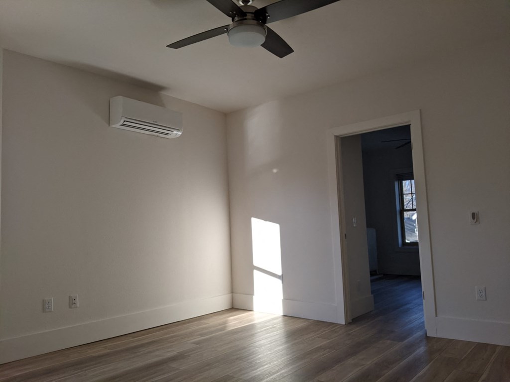 an empty living room with a ceiling fan and a window