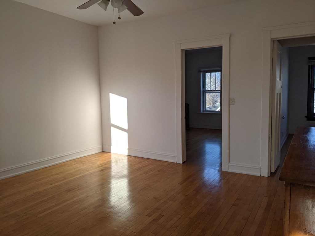 an empty living room with wooden floors and a window