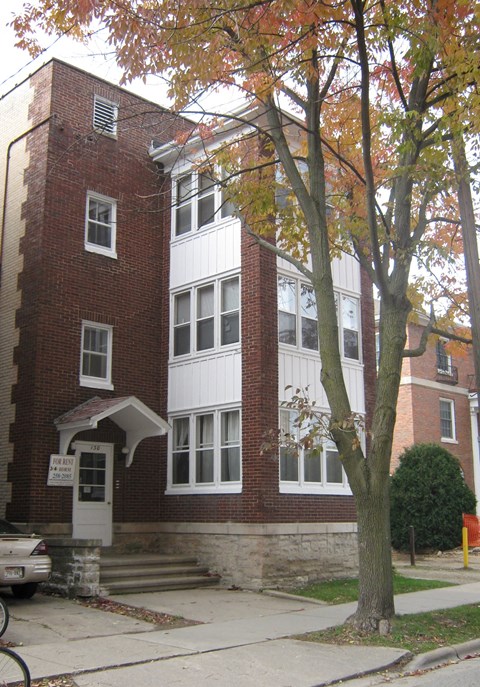 a red brick apartment building with a tree in front