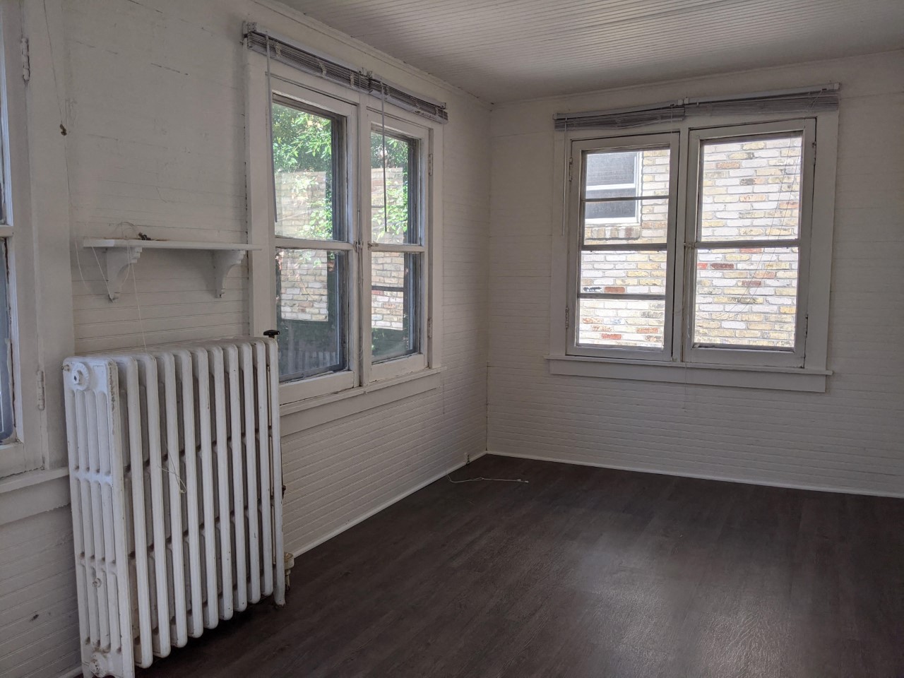 an empty room with a radiator and two windows