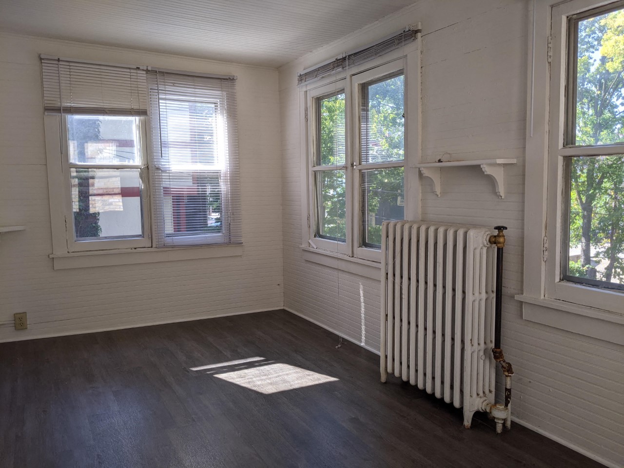 an empty room with a radiator and two windows