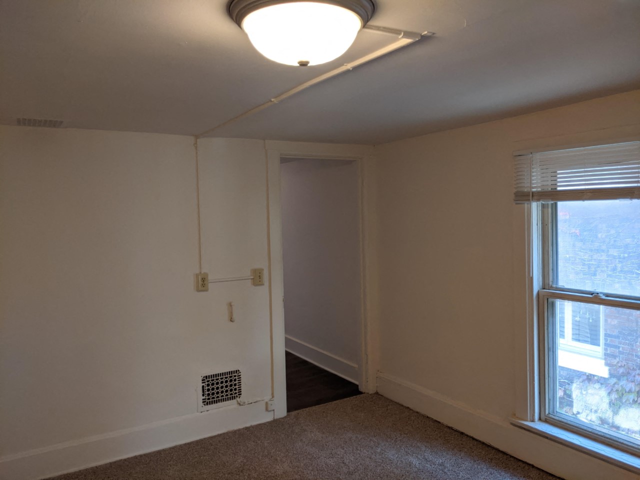 a bedroom with a window and a white wall and a door