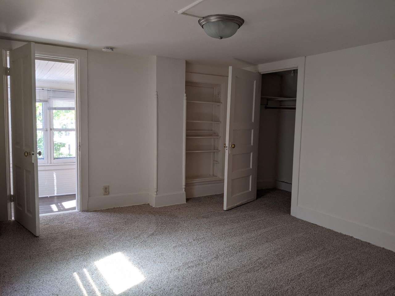 an empty living room with a closet and a window