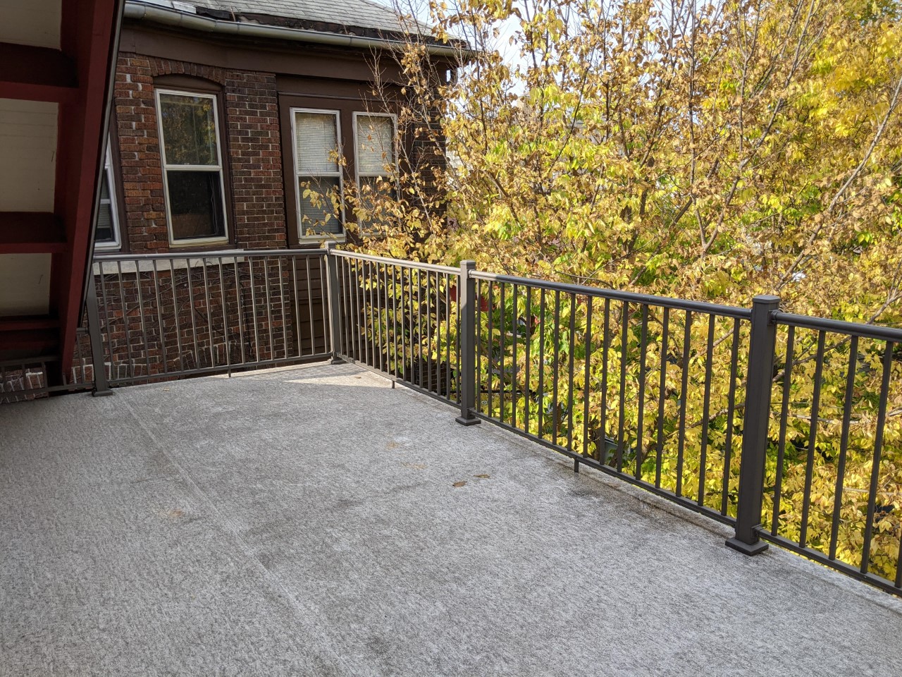 a balcony with a fence and a house behind it
