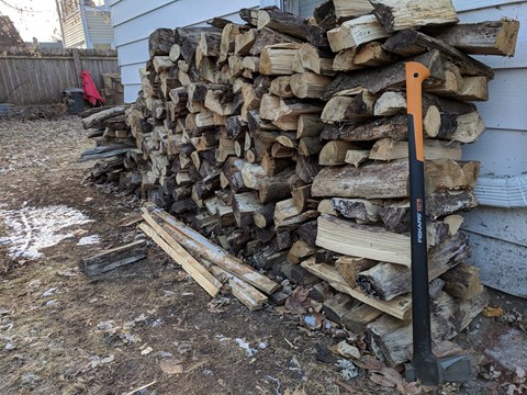 a pile of wood in front of a building with a shovel