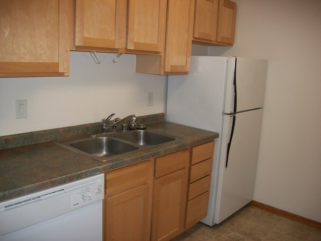 an empty kitchen with a sink and a refrigerator