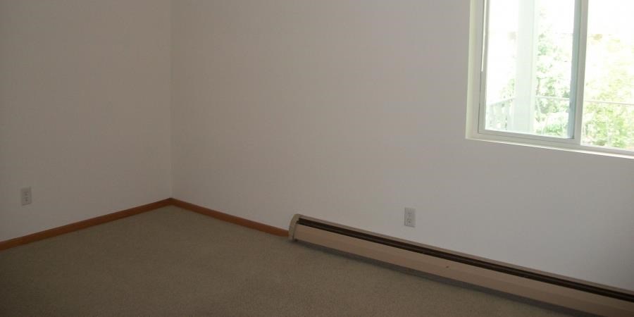 an empty room with a window and a carpet