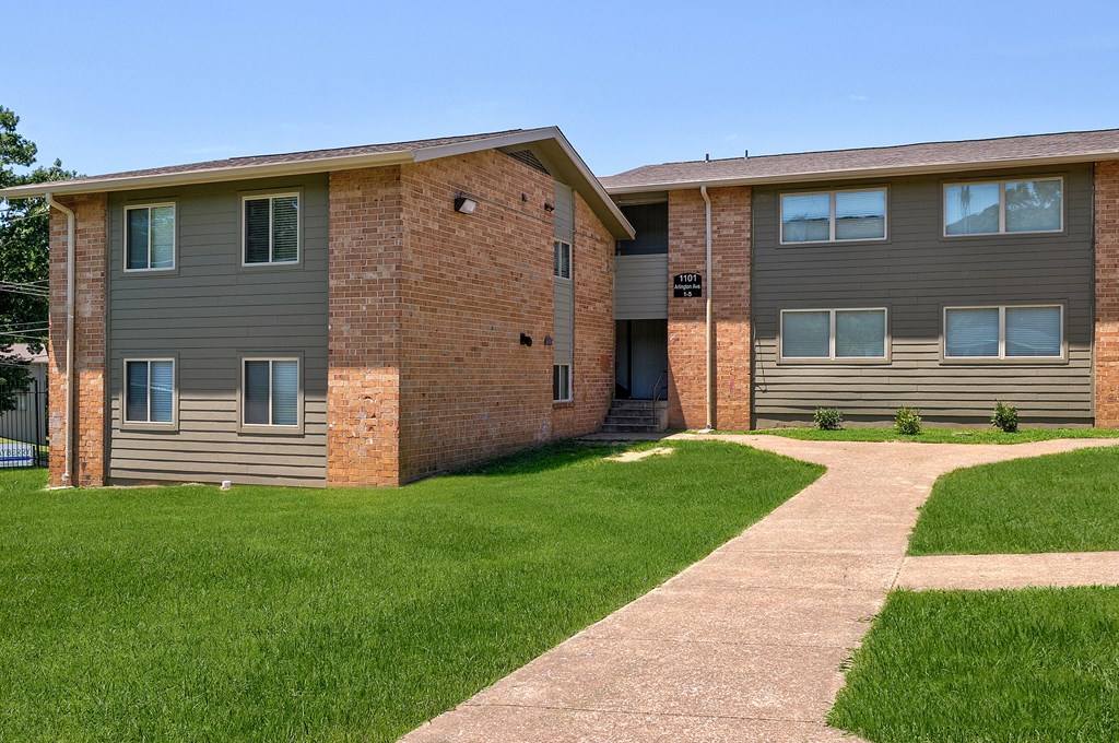 an apartment building with a sidewalk and grass