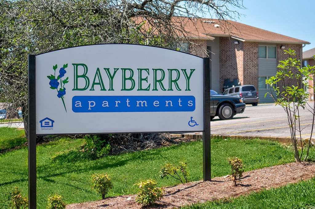 a sign for bayberry apartments in front of a house