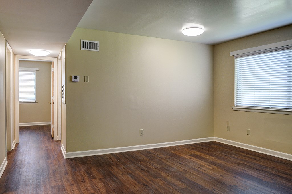 an empty living room with wood floors and a window