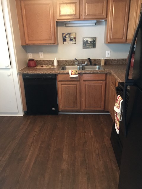 A kitchen with wooden cabinets and a black refrigerator.