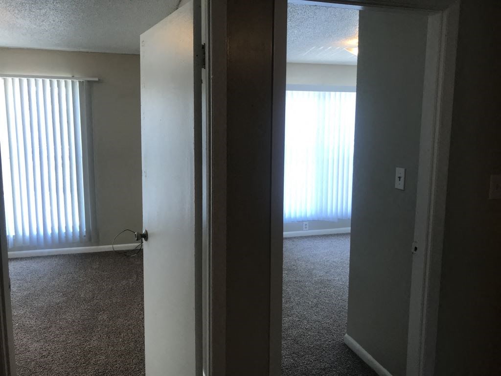 A room with a carpeted floor and a door leading to another room.