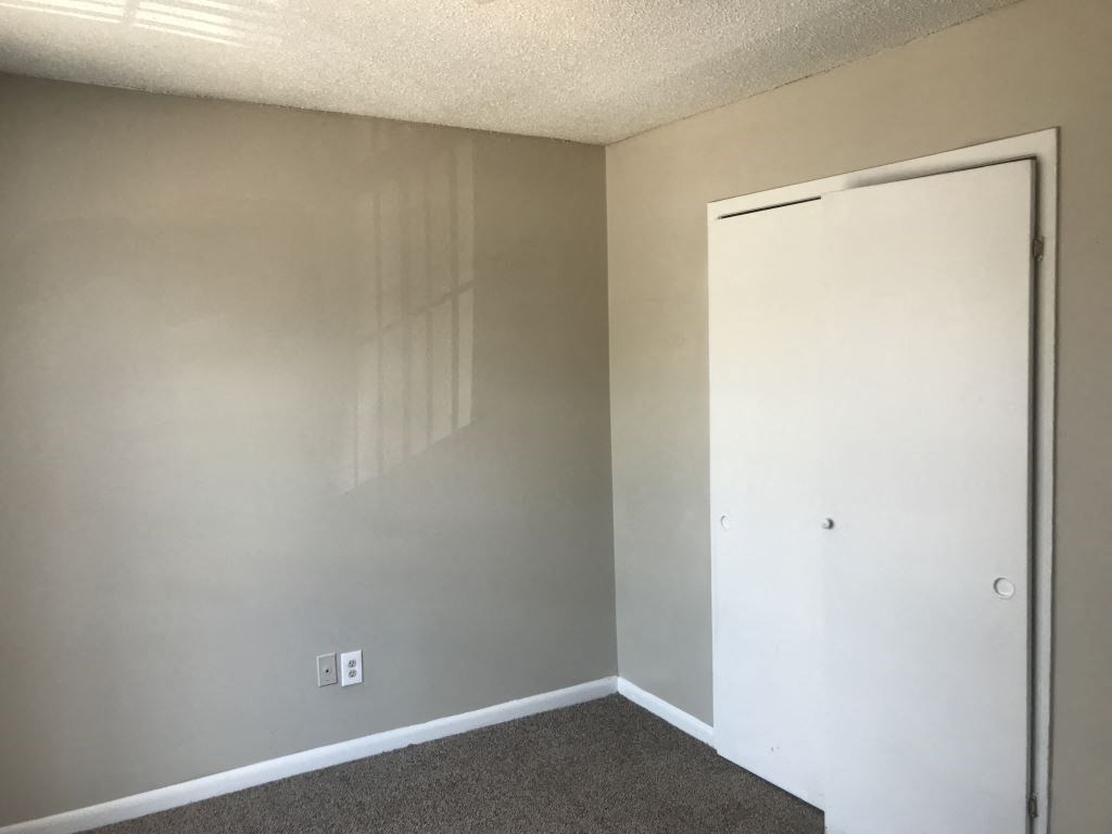 A room with a white door and a light switch on the wall.