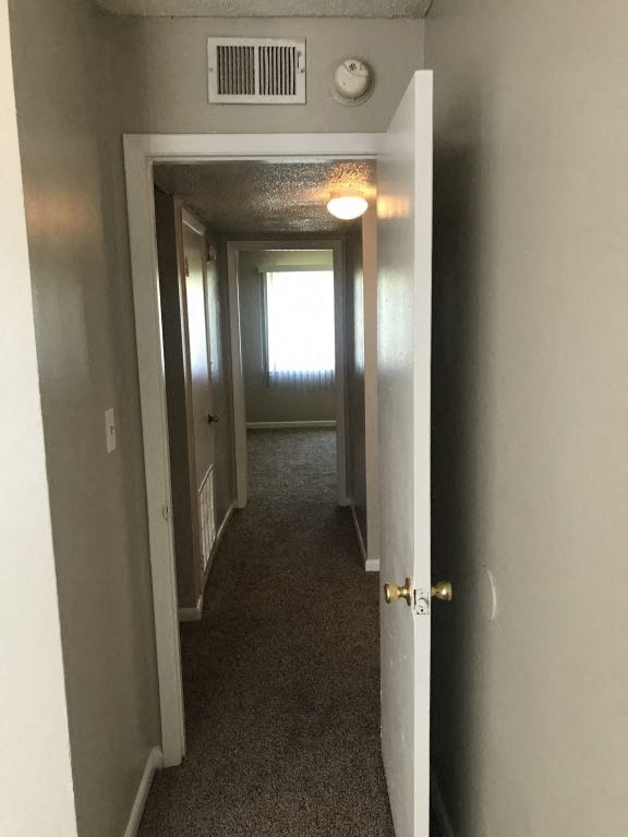 A hallway with a door on the right and a window in the distance.