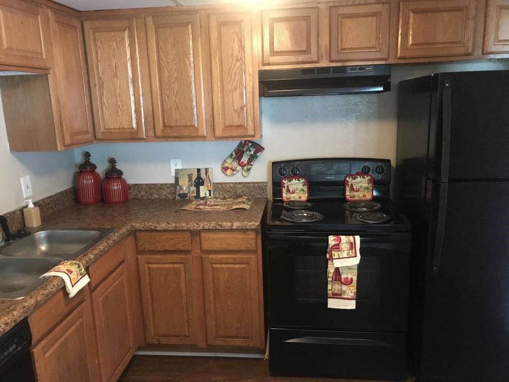 A kitchen with wooden cabinets and a black oven.
