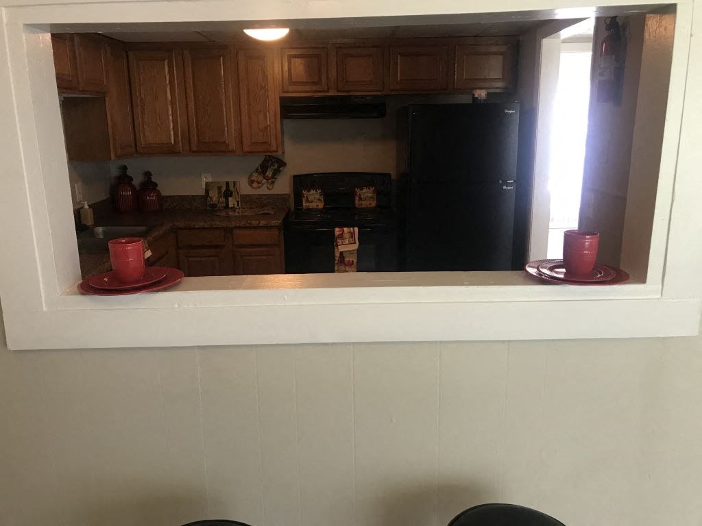 A kitchen with wooden cabinets and a black refrigerator.