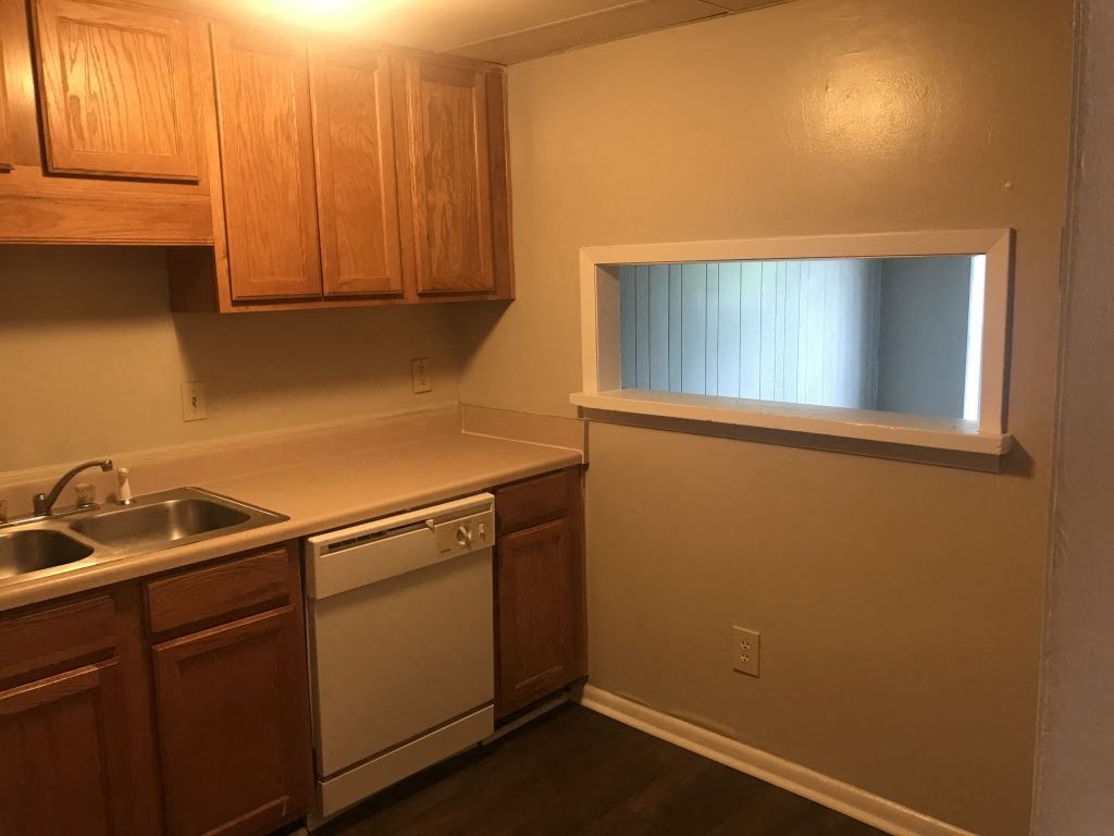 A kitchen with wooden cabinets and a window.