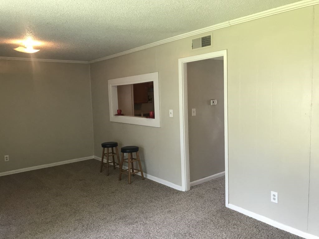A room with a bar stool and a small window.