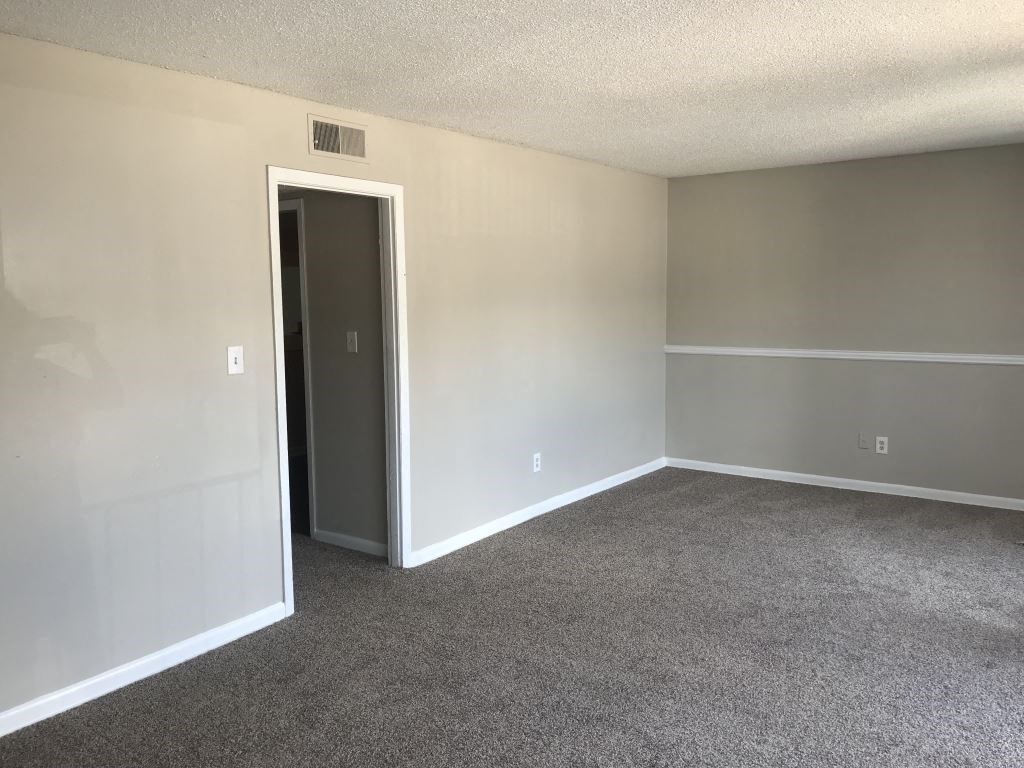 A room with a carpeted floor and a door.