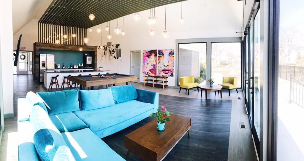 a living room with a blue couch and a kitchen with a pool table