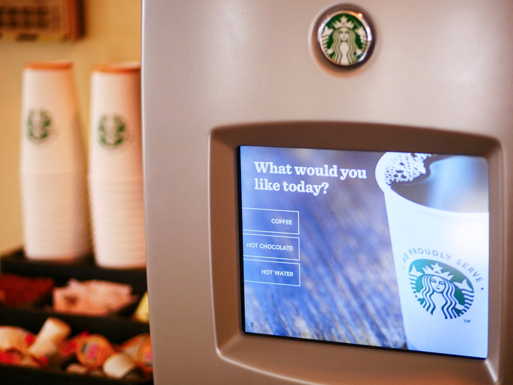 a kiosk with a cup of coffee and a tablet screen on it