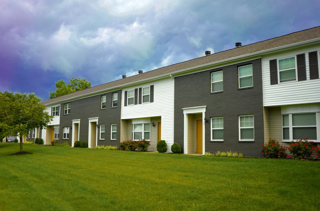 a large apartment building with a green lawn