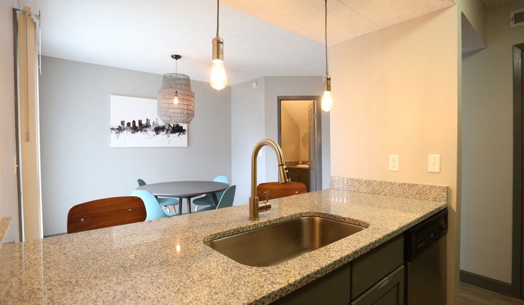 a kitchen counter with a sink and a dining room with a table and chairs