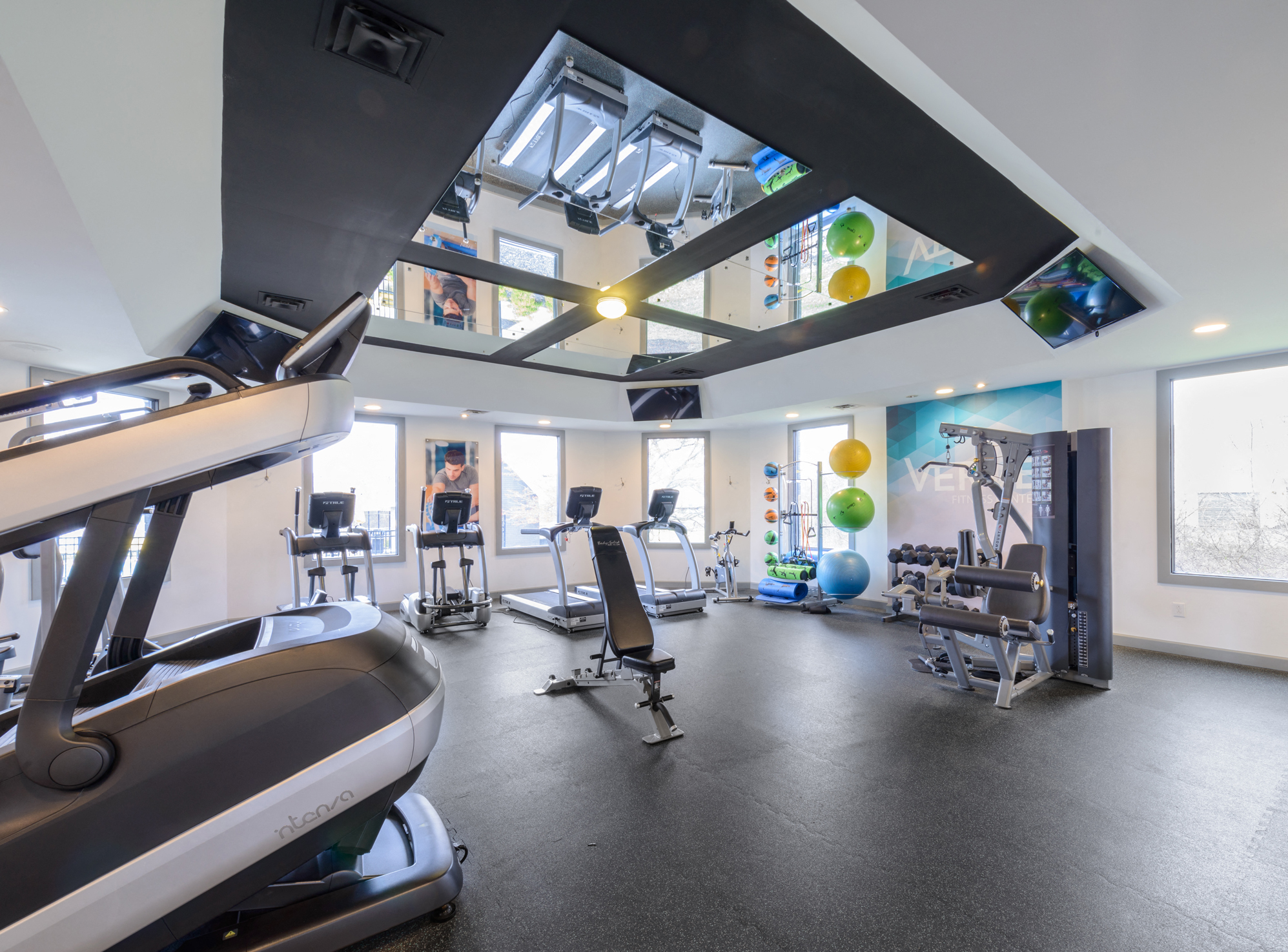 a gym with treadmills and other exercise equipment and windows