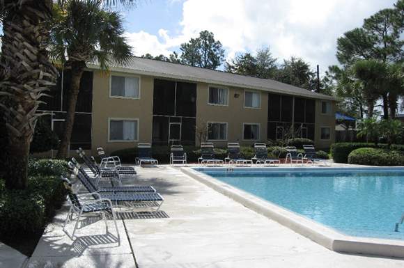 A pool and sun loungers in front of a building.