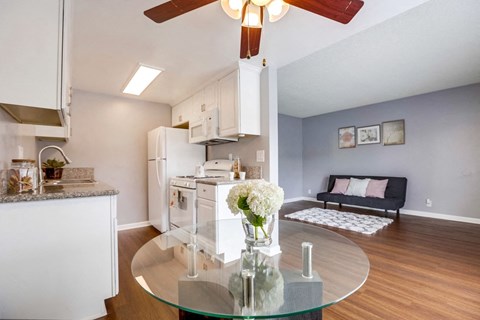 A modern kitchen with a glass table and a ceiling fan.