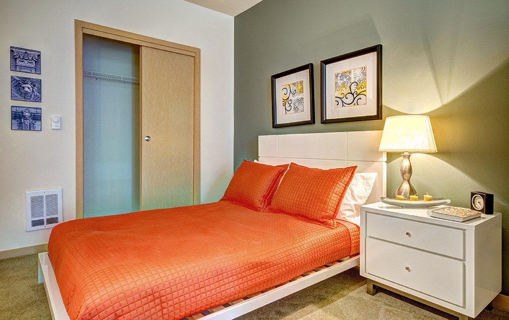 a bedroom with a bed and a nightstand with a lamp