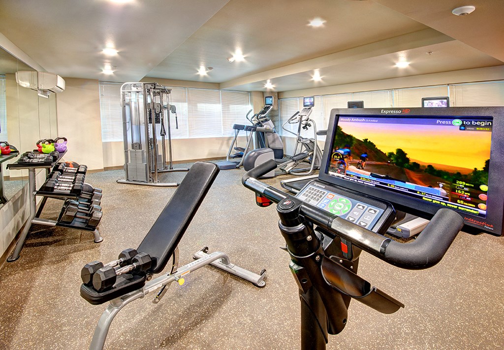 a gym with exercise equipment and a computer on a treadmill