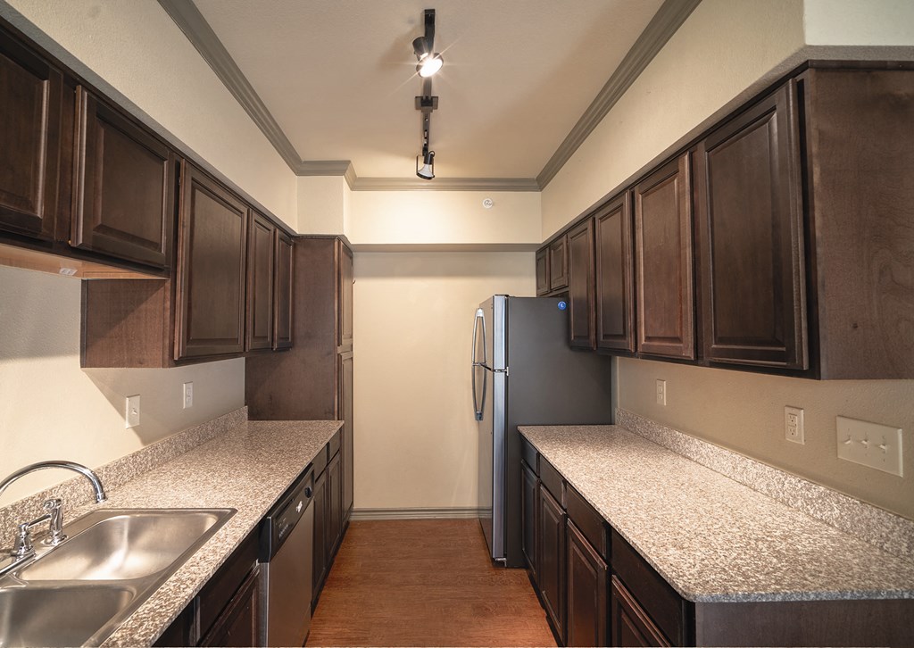 a kitchen with granite counter tops and a stainless steel refrigerator