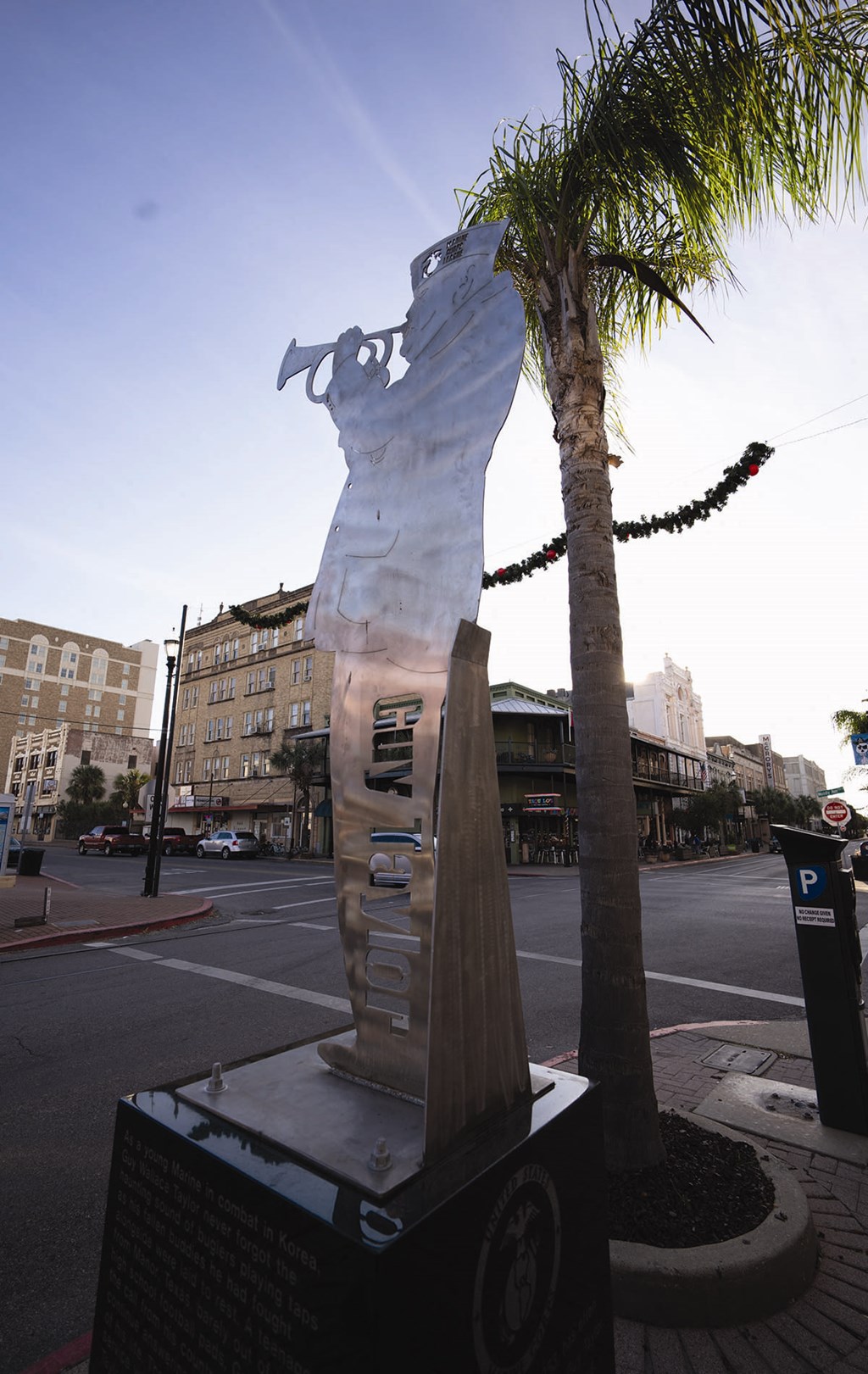 a sculpture on the side of a street next to a palm tree
