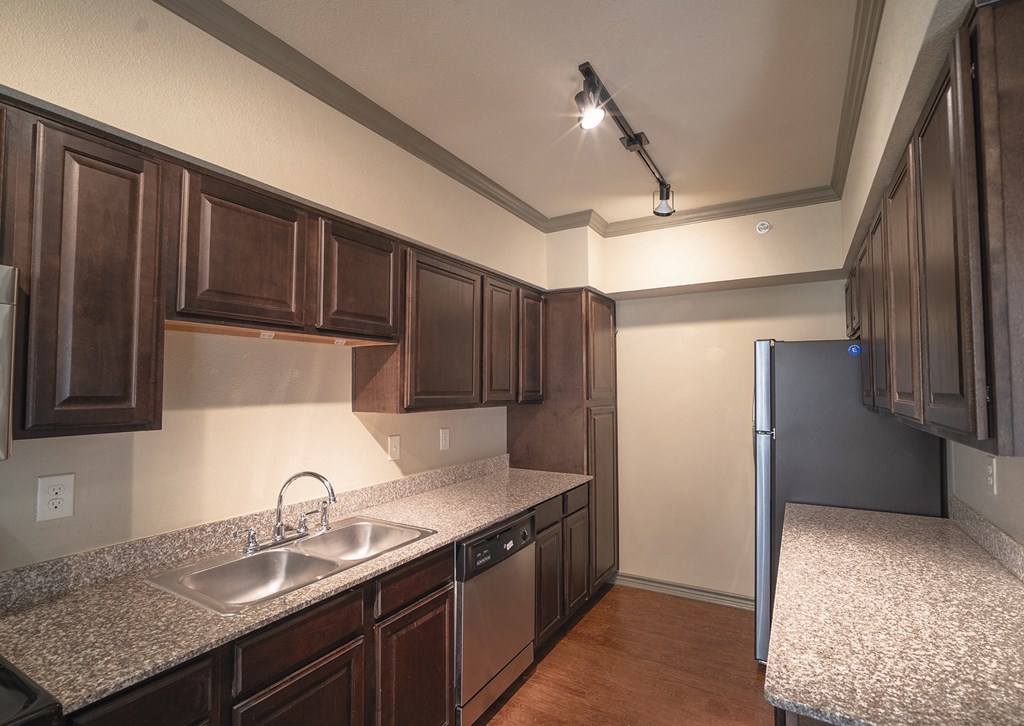 a kitchen with wood cabinets and granite counter tops and a refrigerator