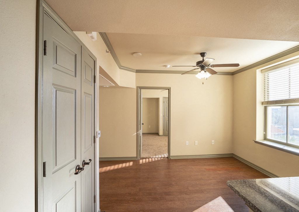 an empty living room with a ceiling fan and a door